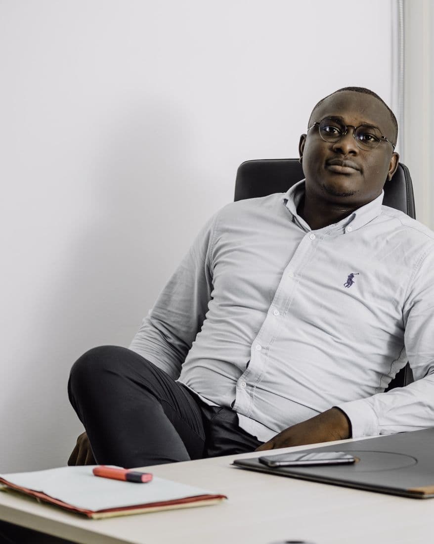 Dossou Cédric ASSAH assis à son bureau, regard posé