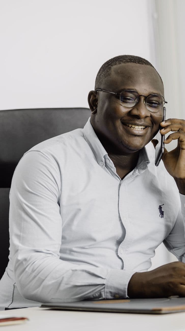 Dossou Cédric ASSAH souriant, au téléphone à son bureau
